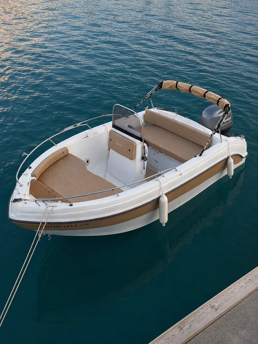 The Angelos moored alongside, with an open deck, bow seating and a rolled canopy on its frame.